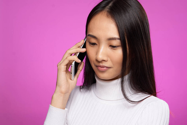csinos barna beszél a telefon fehér pulóver vágott kilátás rózsaszín háttér - Fotó, kép