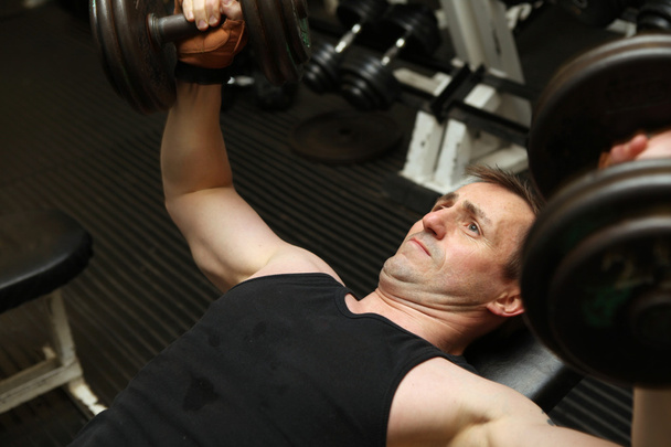 Trainingstrizeps mit freien Gewichten. Männliche Hantelstange über dem Kopf baut Muskelkraft auf - Foto, Bild