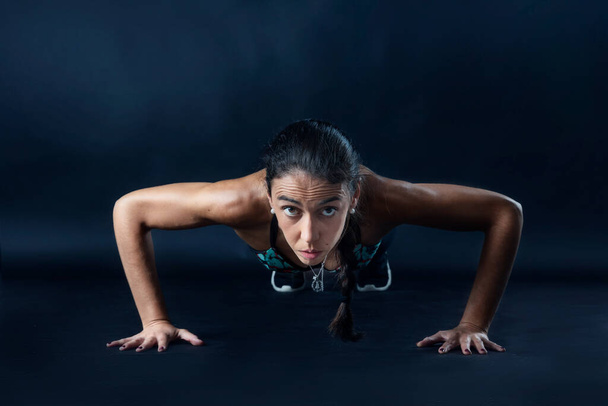 kobieta wykonująca ćwiczenia fitness na ciemnym tle. - Zdjęcie, obraz