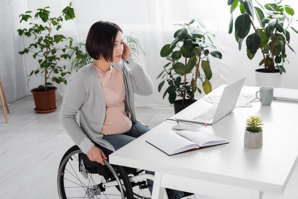 Vammaiset freelancer käyttäen kuulokkeita lähellä kannettavaa tietokonetta ja kannettavan kotona  - Valokuva, kuva
