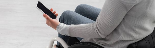 Vue recadrée de la femme handicapée tenant un téléphone portable avec écran blanc à la maison, bannière  - Photo, image