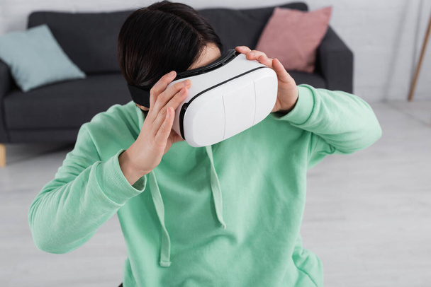 Brunette woman playing video game in vr headset at home  - Photo, Image
