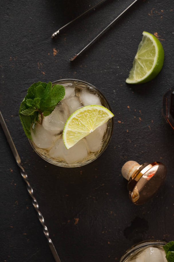 Alcoholische cocktail met rum en ijs en munt op een donkere achtergrond in een bar - Foto, afbeelding