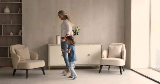 Young mom dancing with little daughter in modern living room - Кадры, видео