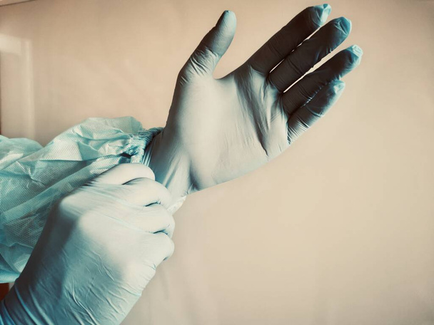 άντρας με μπλε λατέξ ιατρικά γάντια στα χέρια του. Ο επαγγελματίας γιατρός φοράει αποστειρωμένα προστατευτικά γάντια. Προετοιμασία για την εξέταση του ασθενούς. Προσωπική προστασία. - Φωτογραφία, εικόνα