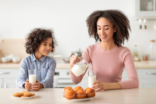 Kis fekete lány és nő tejet iszik - Fotó, kép