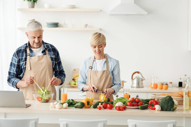 Пара приготовления здорового вегетарианского салата, наслаждаясь процессом на современной уютной кухне, готовить вместе - Фото, изображение