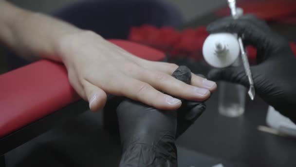 vista parziale di manicure versando olio per cuticole e utilizzando spingicuticole - Filmati, video
