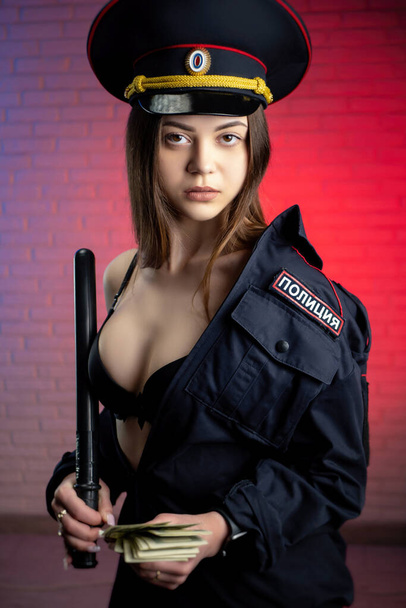 sexy Frau in einer russischen Polizeiuniform mit Schlagstock und Geld. Englische Übersetzung - Foto, Bild