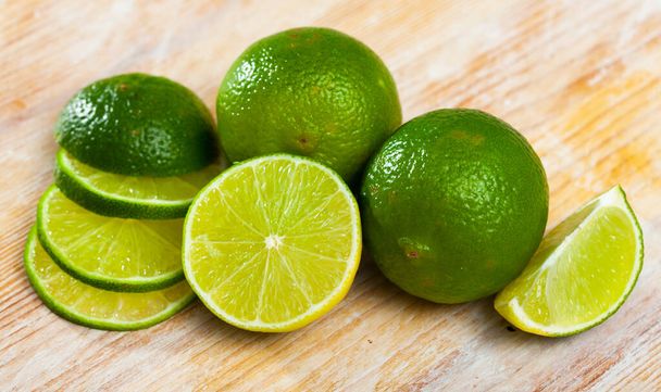 Ripe lime and knife on wooden cutting board - Photo, image