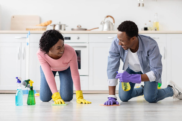 Позитивний чорний чоловік і жінка прибирають підлогу на кухні
 - Фото, зображення