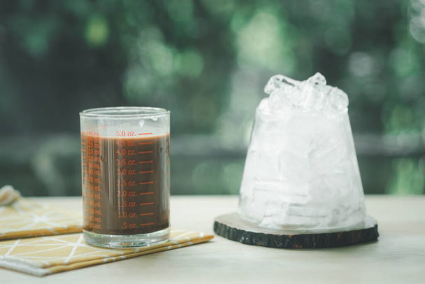 Bardakta sıcak mocha ve tahta masada buz küpleriyle servis edilir. - Fotoğraf, Görsel
