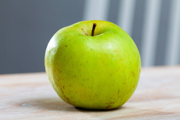 Sweet green single apple on wooden surface - Фото, изображение