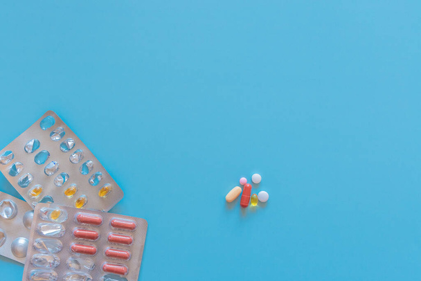 Farmaco colorato sulla superficie turchese e in blister. Compresse, pillole e capsule multicolore su sfondo blu con spazio per la copia. Vista dall'alto del farmaco. - Foto, immagini