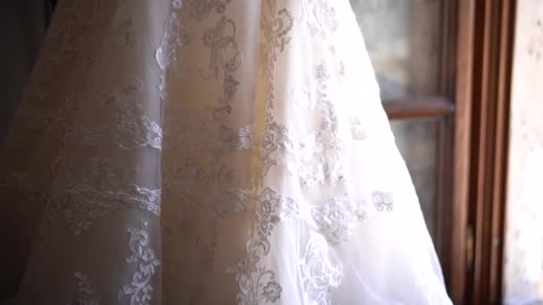 Hermoso vestido de novia con cuentas colgando cerca de la ventana abierta - Imágenes, Vídeo