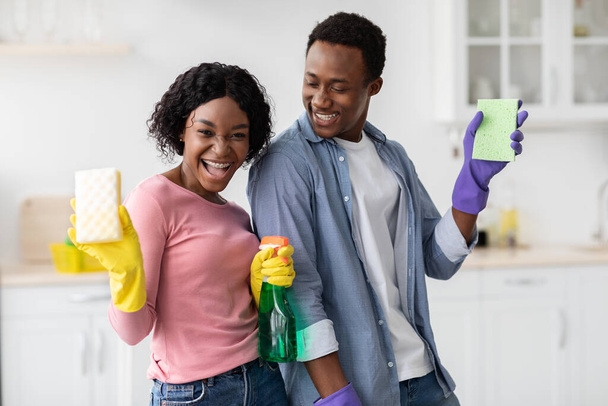 Jovens amantes negros com esponjas e garrafas de spray casa de limpeza - Foto, Imagem