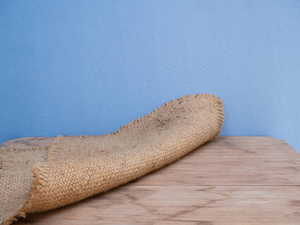 Zakdoek, jute hessian rangschikking op houten tafel en blauwe cementwand achtergrond met kopieerruimte - Foto, afbeelding