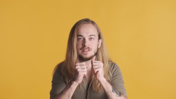 Young long haired blond man looking excited clenching fists rejoicing good deal isolated on yellow background. Celebrating victory expression - Footage, Video
