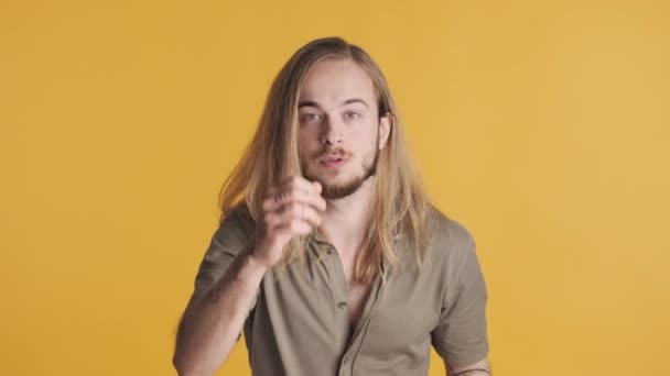 Young long haired blond man looking excited screaming yes rejoicing good news over yellow background. Successful deal - Footage, Video