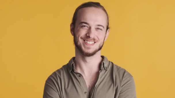 Giovane attraente uomo barbuto cercando felice sinceramente sorridente sulla macchina fotografica su sfondo giallo. espressione del volto felice - Filmati, video