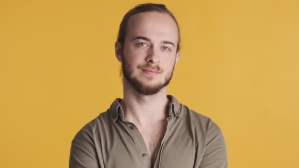 Giovane uomo barbuto attraente vestito in abbigliamento casual cercando fiducioso sorridente sulla macchina fotografica su sfondo giallo. Espressione facciale - Filmati, video