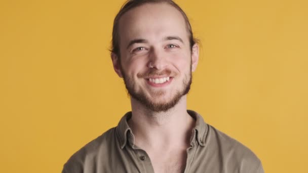 Bello sorridente uomo barbuto cercando felice d'accordo sulla macchina fotografica isolata su sfondo giallo - Filmati, video