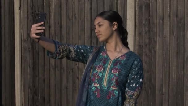 Shalwar Kamezで少数民族の女性ティーンエイジャーは、スマートフォンで自撮りします.ロックオフ - 映像、動画