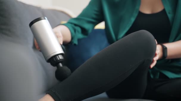 Frau massiert Bein mit Massage-Perkussionsgerät zu Hause. - Filmmaterial, Video
