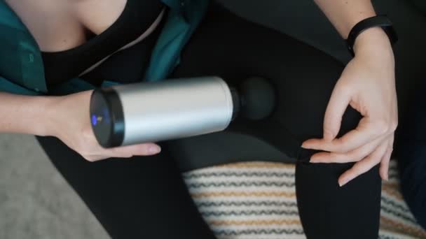 Frau massiert Bein mit Massage-Perkussionsgerät zu Hause. - Filmmaterial, Video