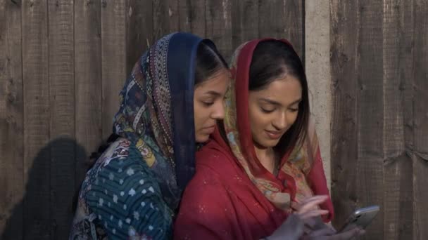 Deux jeunes femmes musulmanes à Shalwar Kameez partageant un téléphone portable. Verrouillé - Séquence, vidéo