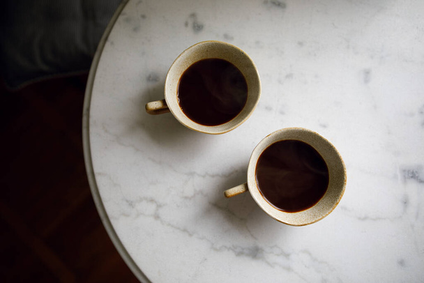 schwarzer Kaffee in zwei Tassen auf einem weißen Marmortisch. Kaffeeritual am Morgen - Foto, Bild