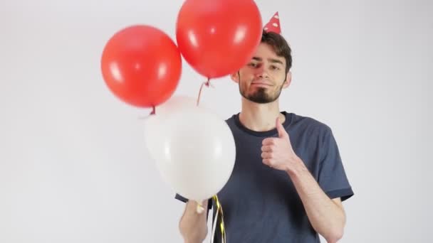 День рождения с воздушными шарами. Красивый парень в красной шляпе на день рождения. Красно-белые шарики. 4K - Кадры, видео