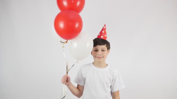 Menino alegre com balões de cor vermelha e branca em uma festa de aniversário alegre. 4k. - Filmagem, Vídeo