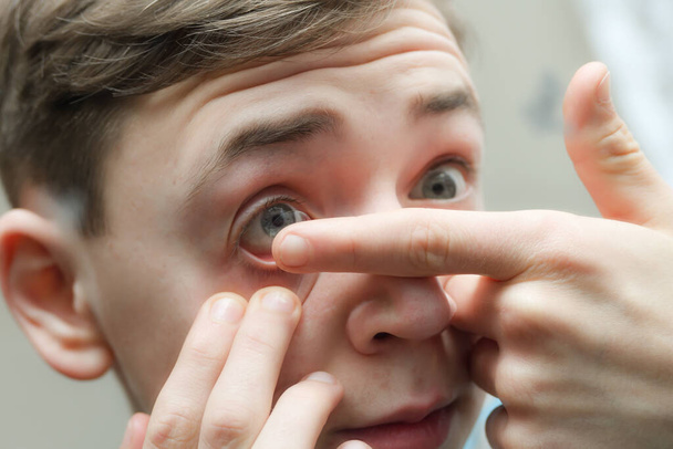 Мужчина надевает контактную линзу на глаз. - Фото, изображение
