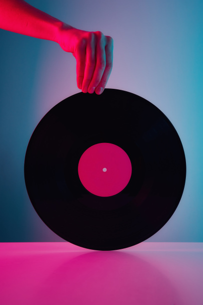 El ele tutuşun, neon ışıklı retro vinil disk. Klasik müzik arkaplanı - Fotoğraf, Görsel
