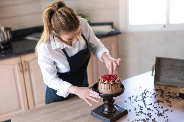 Genç pasta şefi mutfakta meyveli ev yapımı çikolatalı kek pişiriyor. - Fotoğraf, Görsel