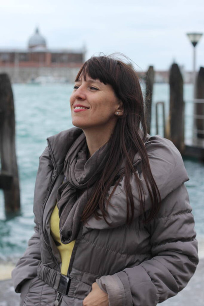 Una mujer que sonríe con ropa casual ordinaria, sobre un fondo borroso de Venecia - Foto, Imagen
