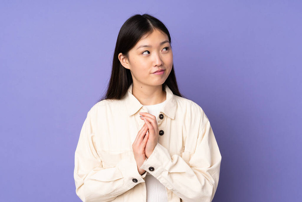 Young asian woman isolated on purple background scheming something - Photo, Image