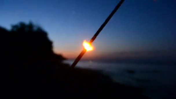 Fuoco del Bengala con scintille brucia di notte al crepuscolo sullo sfondo - Filmati, video