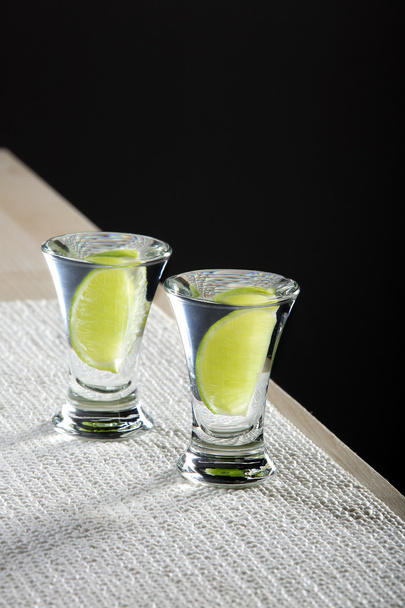 Two glasses of vodka with lime on the table - Fotó, kép