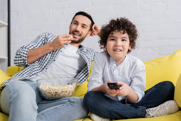 cheerful arabian father and son watching comedy movie at home - Photo, Image