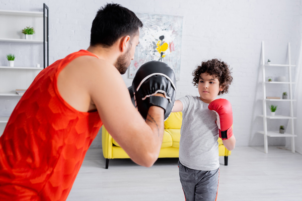 アラビア少年ボクシングとともにお父さんとともにぼやけたフォアグラウンドでリビングルーム  - 写真・画像