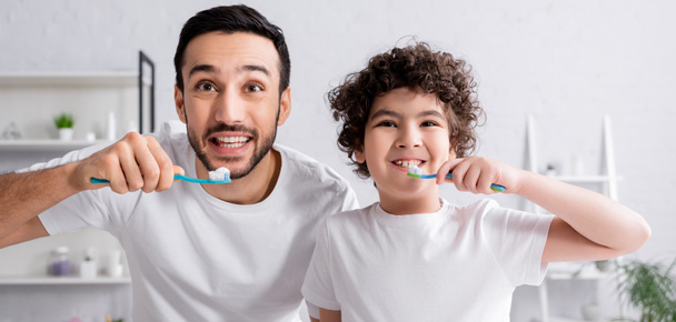 Χαμογελώντας άραβας άντρας και γιος βουρτσίζουν δόντια, λάβαρο  - Φωτογραφία, εικόνα
