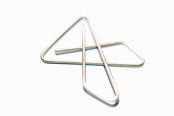 An extreme macro shot with selective focus of an x-style silver metal paper clip set on white background. - Photo, Image