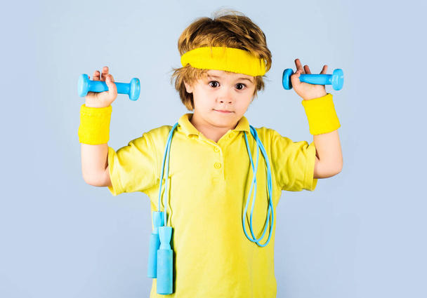Fitness kinderen. Sportieve jongen in sportkleding met springtouw en halters. Kindersportman. - Foto, afbeelding