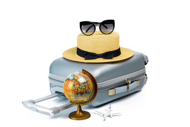 Bagajlar izole edildi. Seyahat aksesuarları bavul, hasır şapka, oyuncak uçak ve dünya beyaz arka planda izole edilmiş minimum seyahat konsepti. Yaz tatili ve ürün reklamları konsepti - Fotoğraf, Görsel