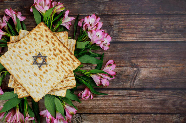 Bovenaanzicht van matzah en roze bloemen. Pascha joodse vakantie. - Foto, afbeelding
