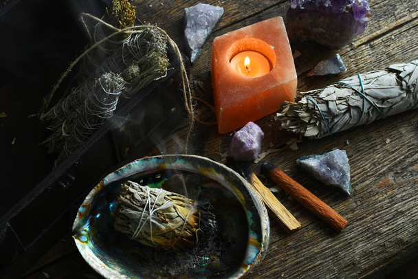 A close up image of a burning white sage smudge stick and healing crystals.  - Photo, Image