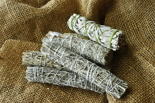 Una imagen de vista superior de varios manojos de salvia sanadora mancha en tela de arpillera.  - Foto, Imagen