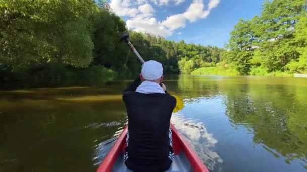 Man peddelt een kano op een rivier in een zonnige zomerdag, Praag, Tsjechië. Avond kajaktocht langs de rivier in de zomer. - Video
